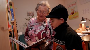 Seniorin mit Kind lesend